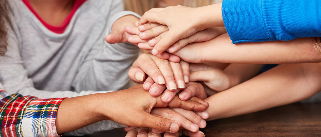 Hände werden aufeinander gelegt als Zeichen für Freundschaft