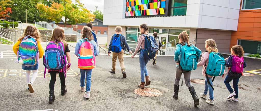 Kinder laufen auf ein Schulgebäude zu