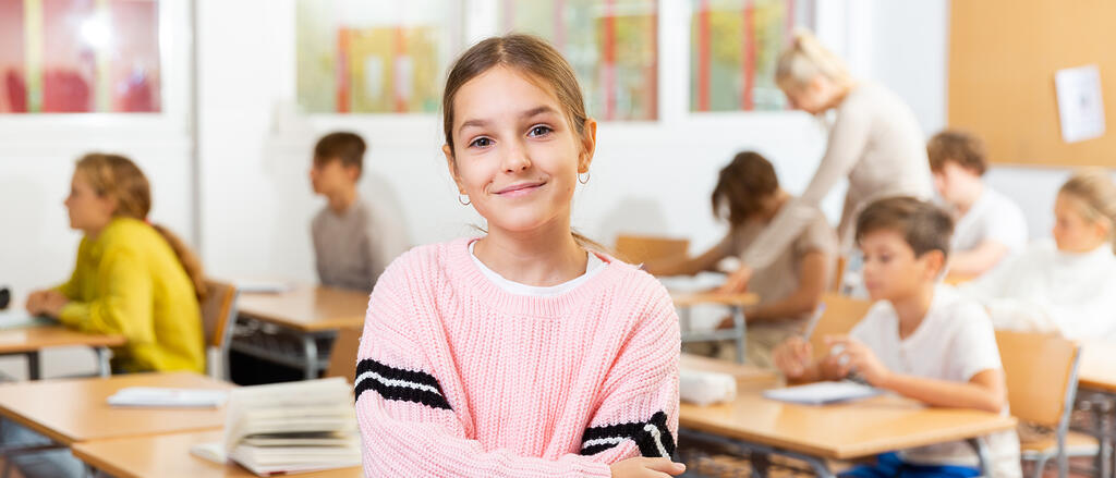 Ein Mädchen steht im Bildfokus im Klassenzimmer